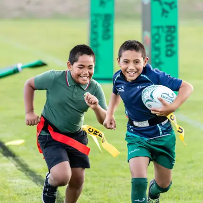 Two boys running with a rugby ball