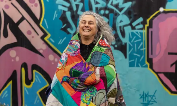 Image if women smiling infornt of graffiti art 